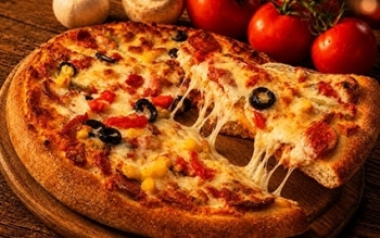 Cheese pizza with olives, peppers, and tomatoes, with a slice being lifted.